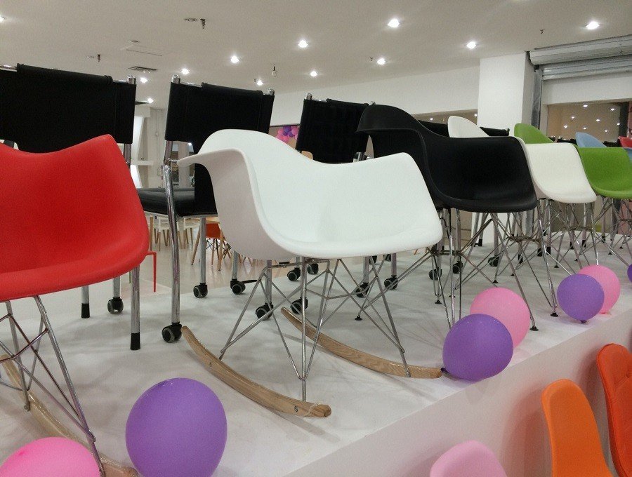 Eames RAR rocking chair in white in room , arms moulded into the shell on a chrome wire base.