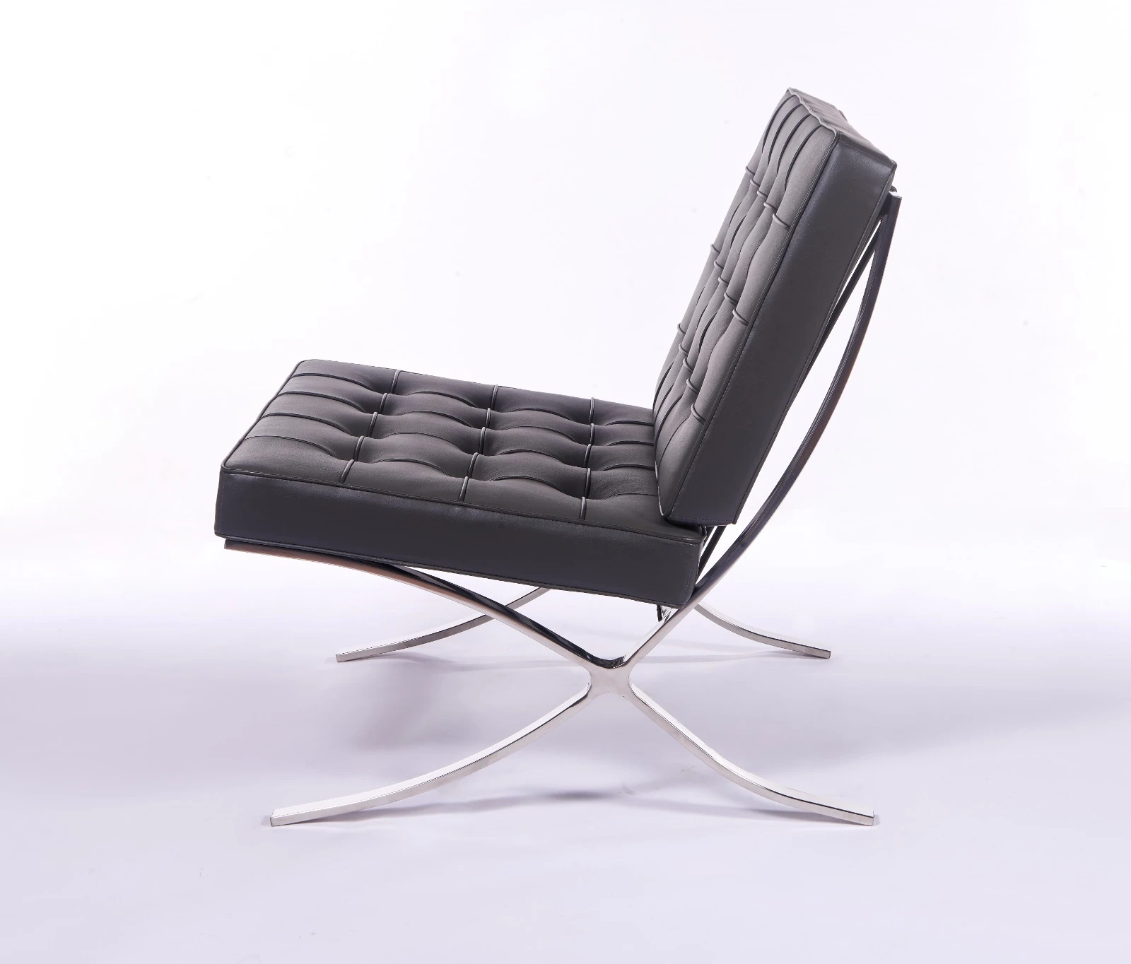Gray Barcelona chair seen from the side, showing the cantilevered polished steel X-frame.