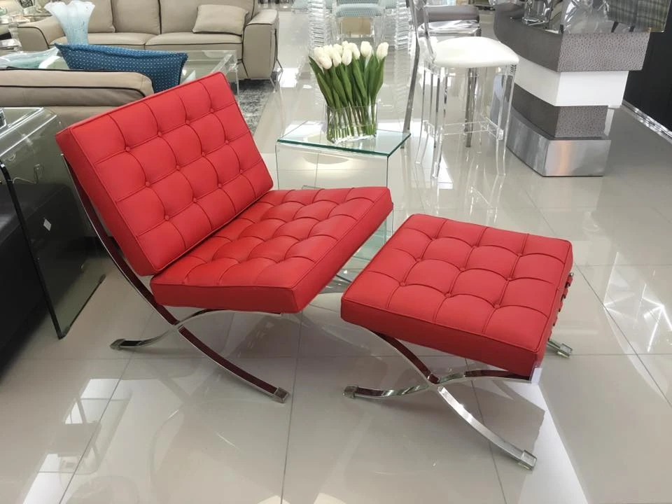 Red leather Barcelona chair and ottoman in tufted leather on a polished steel X-frame, front view. A Barcelona chair with its X-frame and tufted leather, and matching stool
