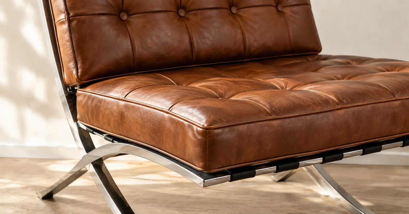 Close-up of tufted leather cushions on a Barcelona chair replica with a polished stainless steel frame